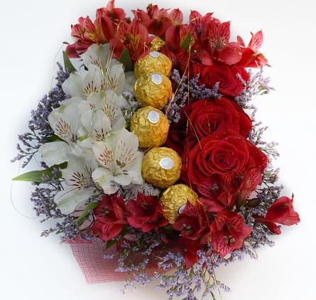 Imagen de Feliz Día Descripcion: Arreglo floral (con esponja, no requiere florero) va con 3 rosas, astromelias, limonium y otras flores variadas que hacen juego con la tonalidad del arreglo, 6 ferreros rocher, brillos, moño y dedicatoria.